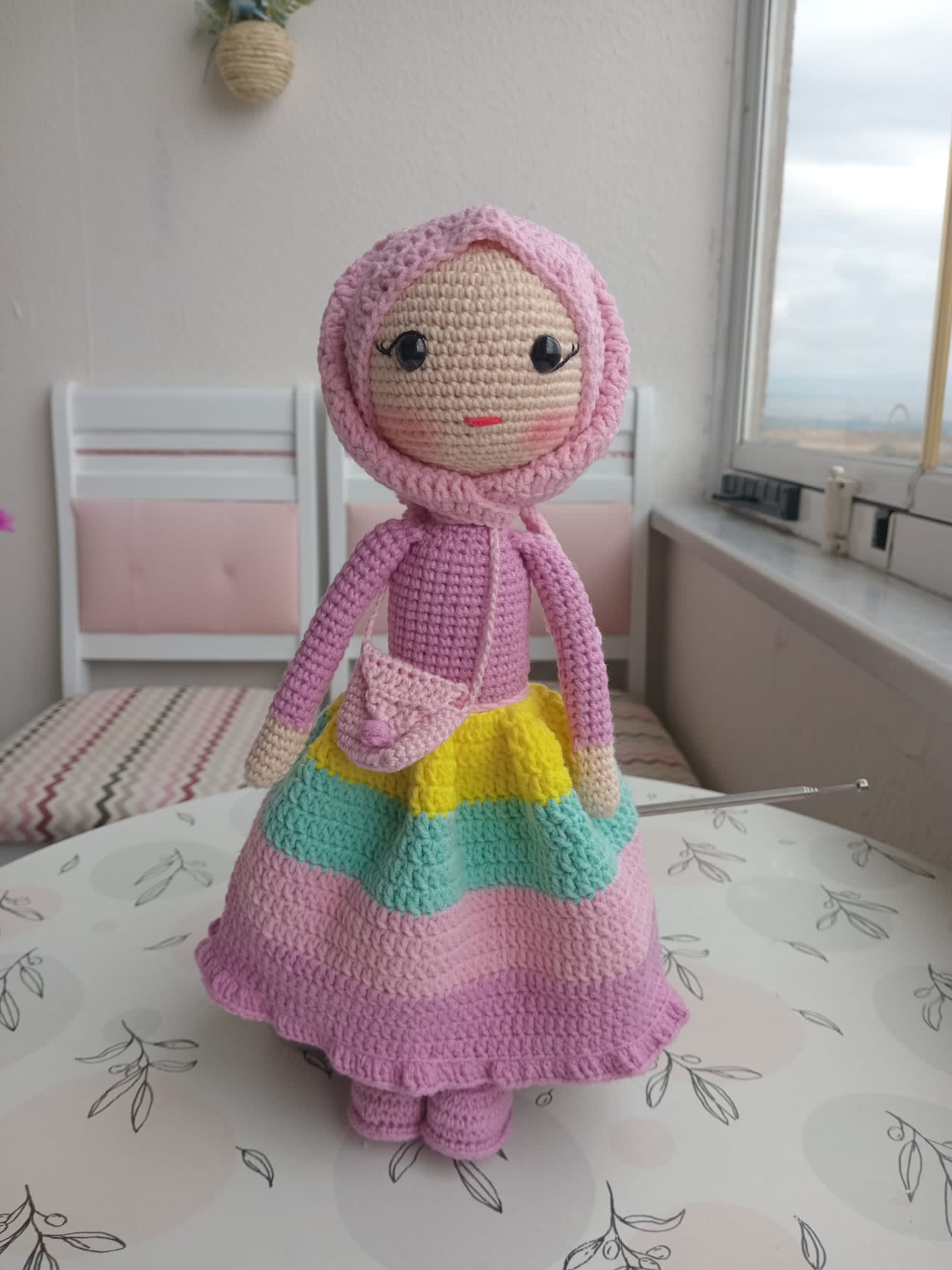 Handmade crocheted doll with a pink hood and colorful skirt